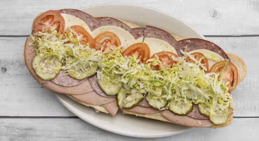 Sub roll with lettuce, tomatoes and various slices of meat and cheese